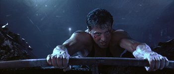 Movie still from “Judge Dredd” (1995), directed by Danny Cannon – A man with blood all over his face and chest is leaning on a railing in the dark; Close Up shot, Low angle