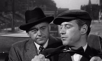 Movie still from “Judgment at Nuremberg” (1961), directed by Stanley Kramer – Two men in hats and ties are looking at each other; Close Up shot, Over the shoulder angle