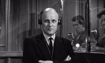 Movie still from “Judgment at Nuremberg” (1961), directed by Stanley Kramer – A man in a suit and tie wearing headphones; Medium shot, Low angle