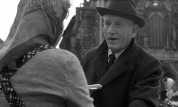 Movie still from “Judgment at Nuremberg” (1961), directed by Stanley Kramer – An older man wearing a hat talking to an older woman; Medium shot, Over the shoulder angle
