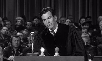 Movie still from “Judgment at Nuremberg” (1961), directed by Stanley Kramer – A man in a court room wearing a robe and holding a microphone; Medium shot, Low angle
