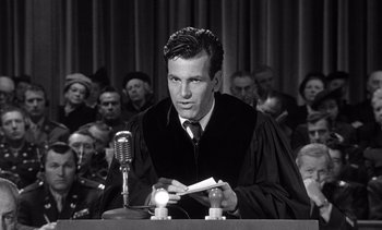 Movie still from “Judgment at Nuremberg” (1961), directed by Stanley Kramer – A man in a court room wearing a robe and holding papers; Medium shot, Low angle