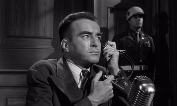 Movie still from “Judgment at Nuremberg” (1961), directed by Stanley Kramer – A man in a suit and tie holding a microphone; Close Up shot, Low angle