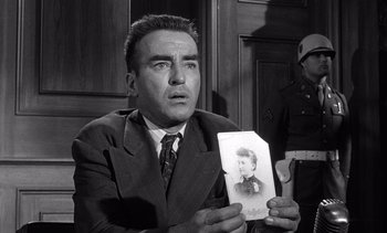 Movie still from “Judgment at Nuremberg” (1961), directed by Stanley Kramer – A man in a suit holding a picture of a woman; Close Up shot, Over the shoulder angle