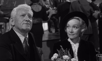 Movie still from “Judgment at Nuremberg” (1961), directed by Stanley Kramer – An older man standing next to an older woman holding flowers; Close Up shot, Low angle