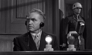 Movie still from “Judgment at Nuremberg” (1961), directed by Stanley Kramer – An older man in a suit and headphones; Medium shot, Over the shoulder angle