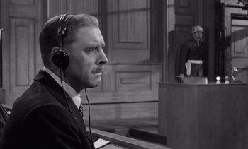 Movie still from “Judgment at Nuremberg” (1961), directed by Stanley Kramer – A man in a court room listening to a judge; Close Up shot, Over the shoulder angle