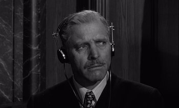 Movie still from “Judgment at Nuremberg” (1961), directed by Stanley Kramer – An older man wearing headphones while wearing a suit; Close Up shot, Low angle
