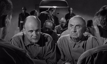 Movie still from “Judgment at Nuremberg” (1961), directed by Stanley Kramer – Two men sitting in front of a group of people; Medium shot, High angle