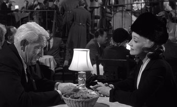 Movie still from “Judgment at Nuremberg” (1961), directed by Stanley Kramer – Two people sitting at a table with a lamp in front of them; Medium shot, Over the shoulder angle