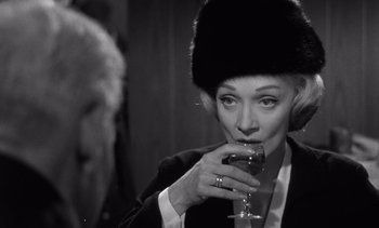 Movie still from “Judgment at Nuremberg” (1961), directed by Stanley Kramer – A black and white photo of a woman drinking a glass; Close Up shot, Over the shoulder angle