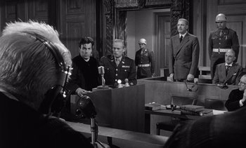 Movie still from “Judgment at Nuremberg” (1961), directed by Stanley Kramer – A group of men standing in front of a judge; Medium shot, Over the shoulder angle