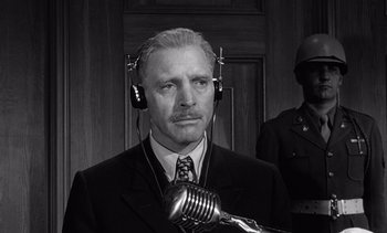 Movie still from “Judgment at Nuremberg” (1961), directed by Stanley Kramer – An older man wearing headphones and holding a microphone in front of his face; Close Up shot, Low angle