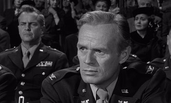 Movie still from “Judgment at Nuremberg” (1961), directed by Stanley Kramer – A man in a military uniform sitting in front of an audience; Close Up shot, Over the shoulder angle