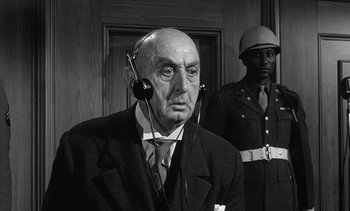 Movie still from “Judgment at Nuremberg” (1961), directed by Stanley Kramer – An older man wearing a suit and tie and headphones; Close Up shot, Low angle