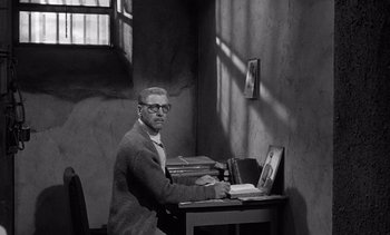 Movie still from “Judgment at Nuremberg” (1961), directed by Stanley Kramer – A black and white photo of a man sitting at a desk; Wide shot, High angle
