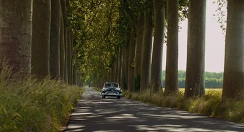 Movie still from “Julie & Julia” (2009), directed by Nora Ephron – A car driving down a tree - lined street; Extreme Wide shot, High angle