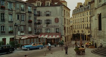 Movie still from “Julie & Julia” (2009), directed by Nora Ephron – An old fashioned car parked in front of an old fashioned restaurant; Extreme Wide shot, High angle