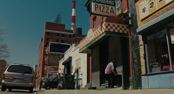 Movie still from “Julie & Julia” (2009), directed by Nora Ephron – A man standing in front of a pizza shop; Extreme Wide shot, High angle