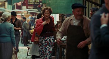 Movie still from “Julie & Julia” (2009), directed by Nora Ephron – An older woman walking down the street in a market; Medium shot, Over the shoulder angle