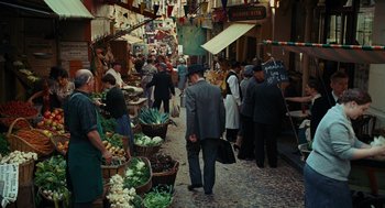 Movie still from “Julie & Julia” (2009), directed by Nora Ephron – A group of people walking down a street with baskets of vegetables; Wide shot, High angle