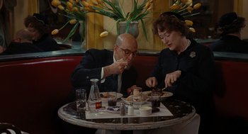 Movie still from “Julie & Julia” (2009), directed by Nora Ephron – A man and a woman sitting at a table eating food; Medium shot, Over the shoulder angle
