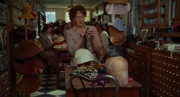 Movie still from “Julie & Julia” (2009), directed by Nora Ephron – An older woman looking at a hat on a table; Medium shot, Over the shoulder angle