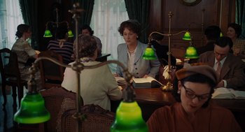 Movie still from “Julie & Julia” (2009), directed by Nora Ephron – A group of people sitting at a table with green lamps; Medium shot, Over the shoulder angle