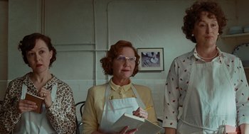 Movie still from “Julie & Julia” (2009), directed by Nora Ephron – An older woman wearing an apron holding a book; Medium shot, Low angle