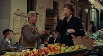 Movie still from “Julie & Julia” (2009), directed by Nora Ephron – A man and a woman eating apples at a market; Medium shot, Over the shoulder angle