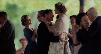 Movie still from “Julie & Julia” (2009), directed by Nora Ephron – A man and a woman hugging each other in front of a group of people; Medium shot, Over the shoulder angle