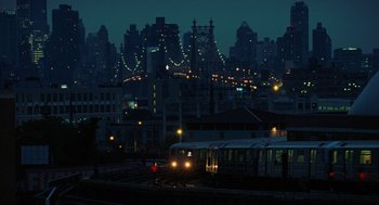 Movie still from “Julie & Julia” (2009), directed by Nora Ephron – A train on the tracks in front of a large city at night; Extreme Wide shot, High angle