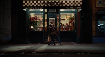 Movie still from “Julie & Julia” (2009), directed by Nora Ephron – Two people walking on the sidewalk in front of a pizza shop; Wide shot, High angle
