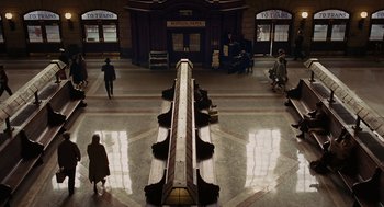Movie still from “Julie & Julia” (2009), directed by Nora Ephron – People are walking in a train station with benches; Extreme Wide shot, High angle