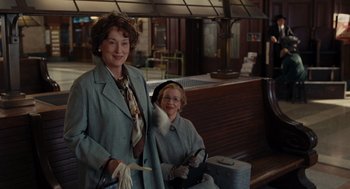 Movie still from “Julie & Julia” (2009), directed by Nora Ephron – A woman and a child standing next to each other in front of a bench; Medium shot, Over the shoulder angle