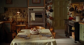 Movie still from “Julie & Julia” (2009), directed by Nora Ephron – A table with a basket of fruit on top of it in a kitchen; Wide shot, High angle