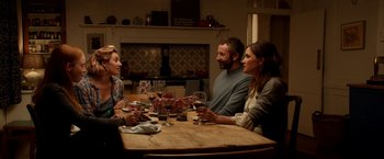 Movie still from “Juliet, Naked” (2018), directed by Jesse Peretz – A group of people sitting around a table with wine glasses; Medium shot, High angle