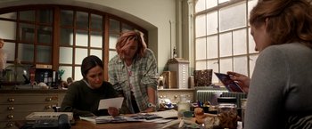 Movie still from “Juliet, Naked” (2018), directed by Jesse Peretz – Two people are sitting at a table looking at a piece of paper; Medium shot, Over the shoulder angle