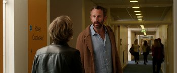 Movie still from “Juliet, Naked” (2018), directed by Jesse Peretz – A man and a woman standing next to each other in a hallway; Medium shot, Over the shoulder angle