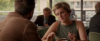 Movie still from “Juliet, Naked” (2018), directed by Jesse Peretz – A woman sitting in front of a man in a green shirt; Close Up shot, Over the shoulder angle