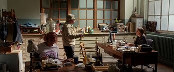 Movie still from “Juliet, Naked” (2018), directed by Jesse Peretz – An older man standing in front of a table; Wide shot, High angle