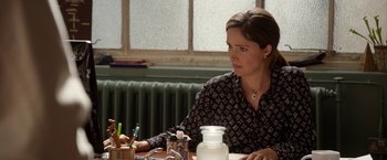 Movie still from “Juliet, Naked” (2018), directed by Jesse Peretz – A woman sitting at a table in front of a window; Close Up shot, Over the shoulder angle