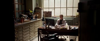 Movie still from “Juliet, Naked” (2018), directed by Jesse Peretz – A woman sitting at a desk in front of a computer; Wide shot, High angle