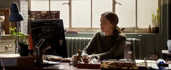 Movie still from “Juliet, Naked” (2018), directed by Jesse Peretz – A woman sitting at a table looking at a computer screen; Medium shot, Over the shoulder angle