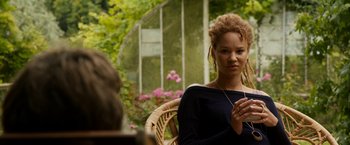 Movie still from “Juliet, Naked” (2018), directed by Jesse Peretz – A woman sitting in front of a window with flowers; Close Up shot, Over the shoulder angle