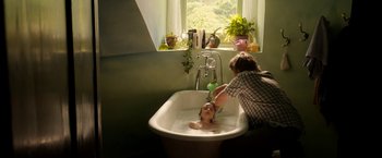 Movie still from “Juliet, Naked” (2018), directed by Jesse Peretz – A young child is being bathed in a sink; Medium shot, Over the shoulder angle