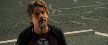 Movie still from “Juliet, Naked” (2018), directed by Jesse Peretz – A person wearing glasses on the side of the road; Close Up shot, Over the shoulder angle