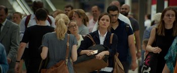 Movie still from “Juliet, Naked” (2018), directed by Jesse Peretz – A group of people standing around each other holding bags; Medium shot, Over the shoulder angle