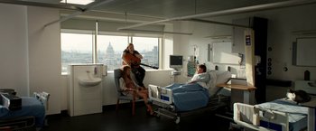 Movie still from “Juliet, Naked” (2018), directed by Jesse Peretz – A group of people sitting in a room with a hospital bed; Wide shot, High angle