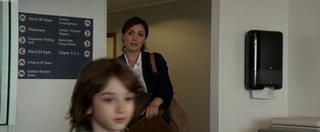 Movie still from “Juliet, Naked” (2018), directed by Jesse Peretz – A woman holding a purse while standing next to a child; Medium shot, Over the shoulder angle